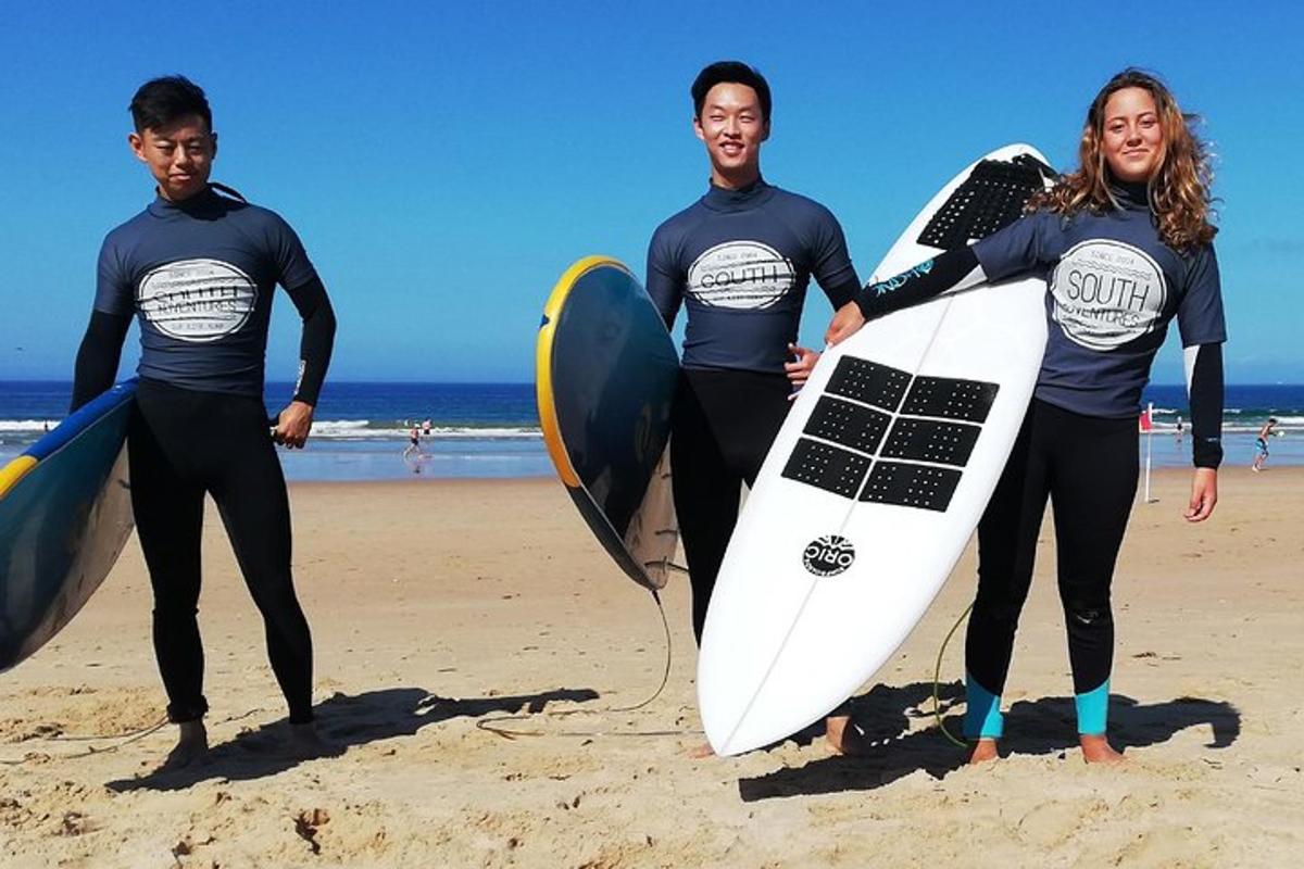 un grup de trei persoane care stau pe plajă cu plăci de surf