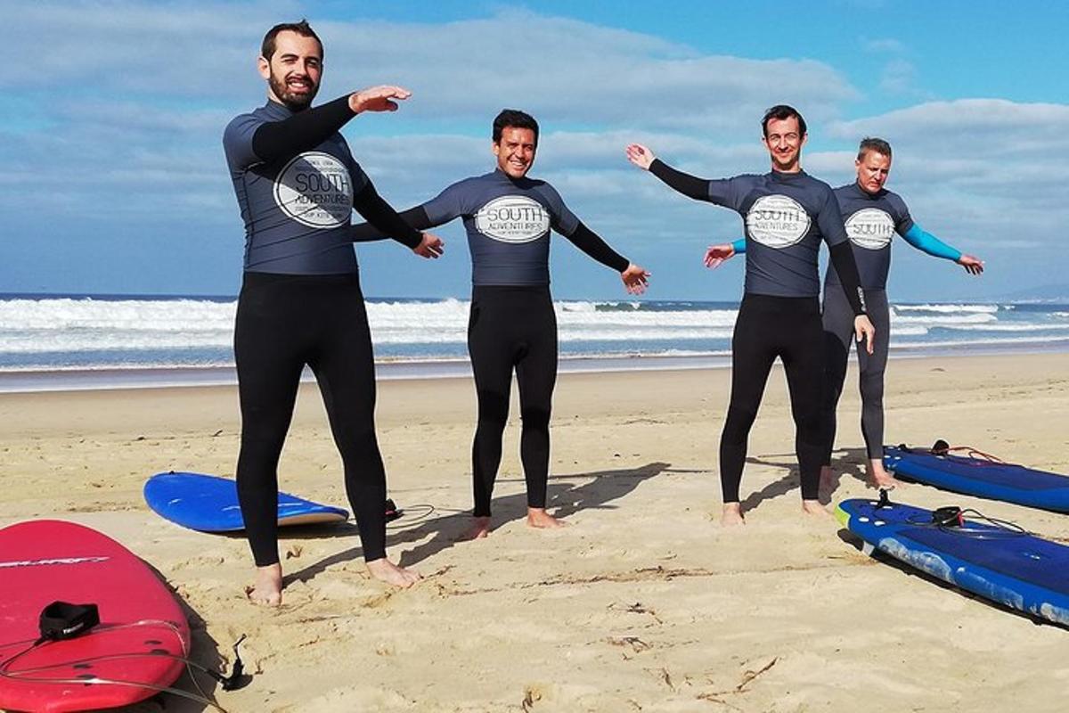 skupina moških v neoprenskih oblekah, ki stojijo na plaži