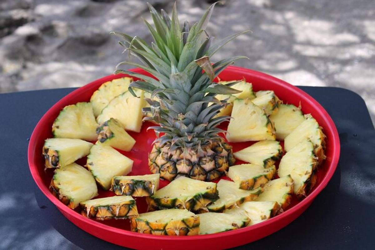 un bol vermell ple de pinya i altres fruites