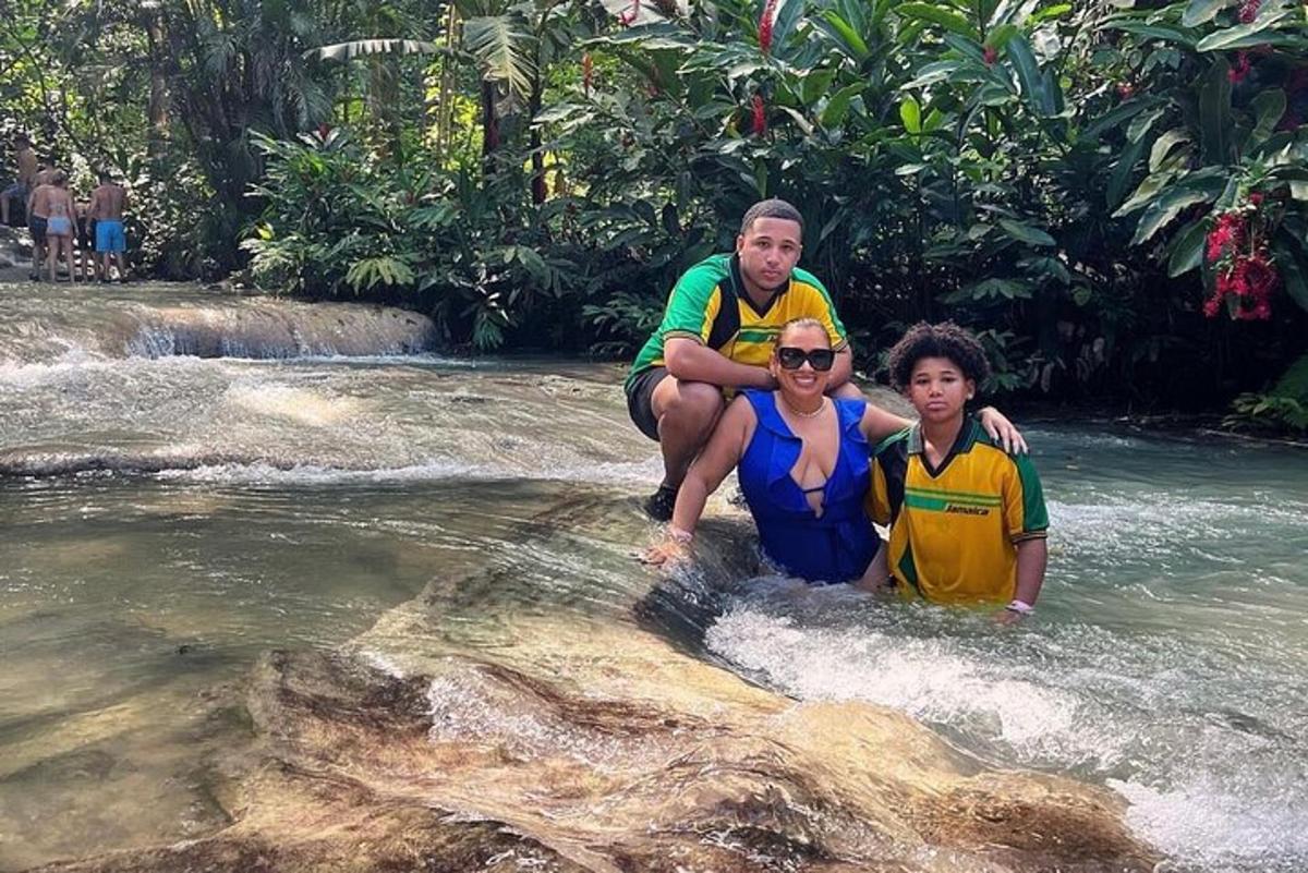 Un hombre y dos niños de pie sobre una roca en un río.