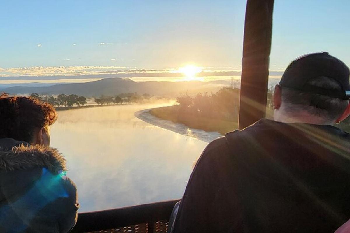 two people watching the sun rise over a lake