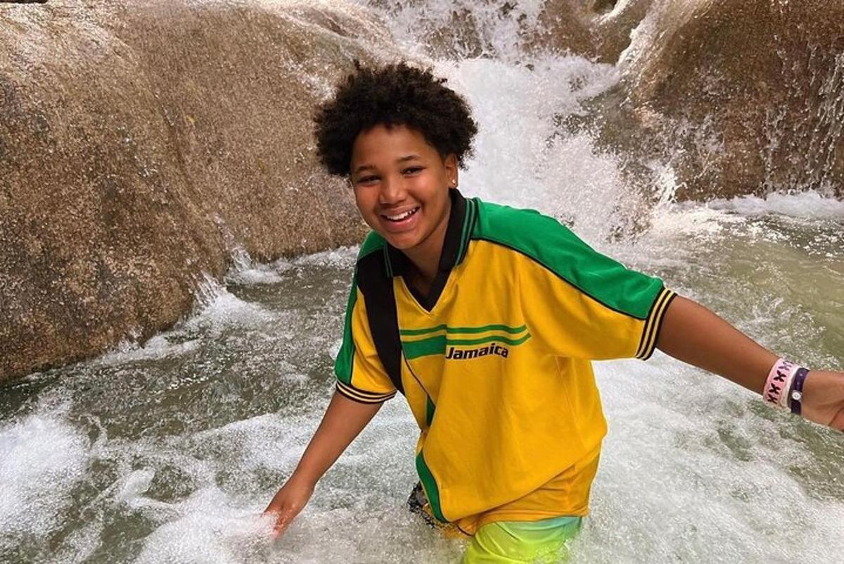 seorang budak lelaki berdiri di dalam air di air terjun