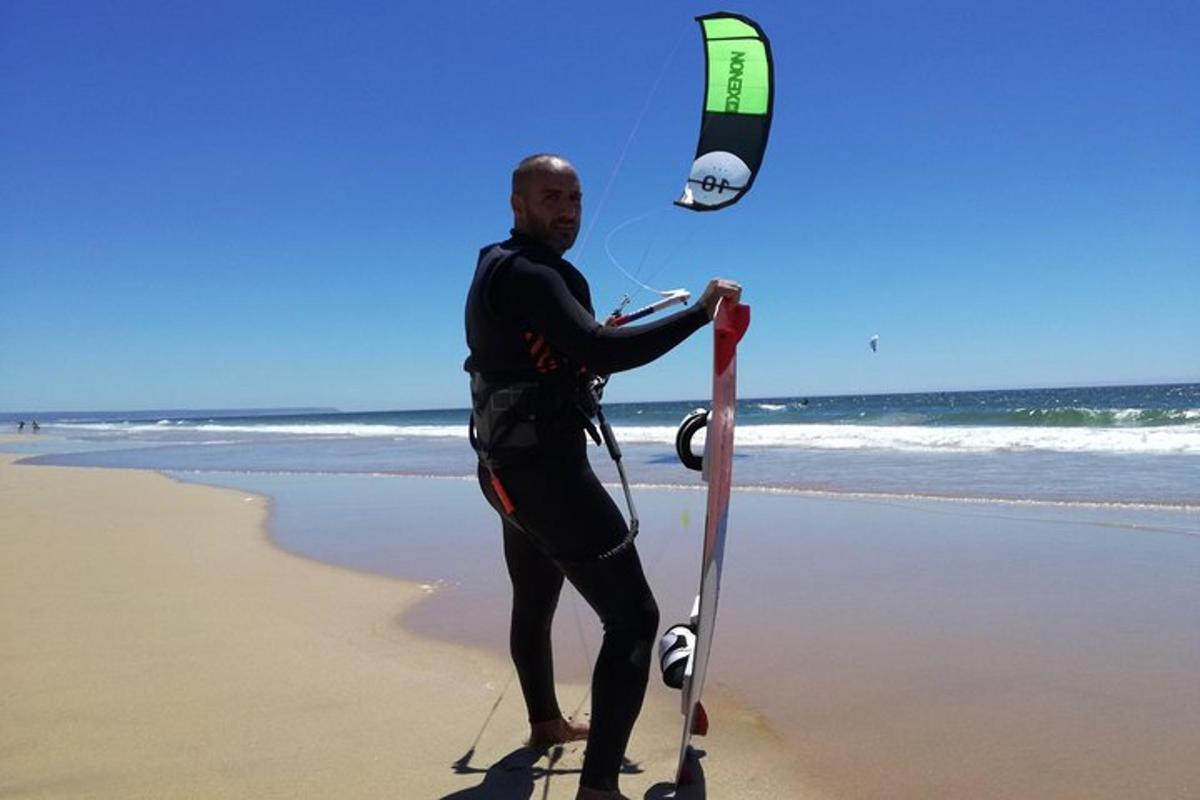 un uomo in piedi sulla spiaggia con un aquilone
