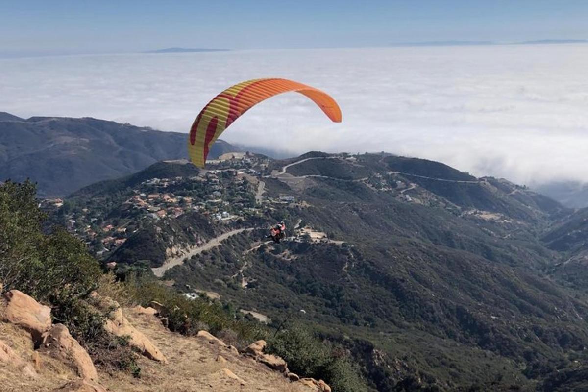 شخص يطير بمظلة على قمة جبل