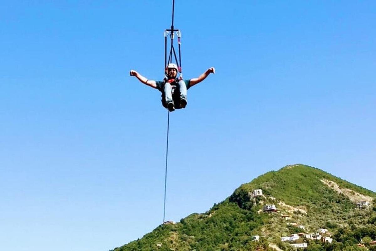 a man hanging from a zip line over a hill