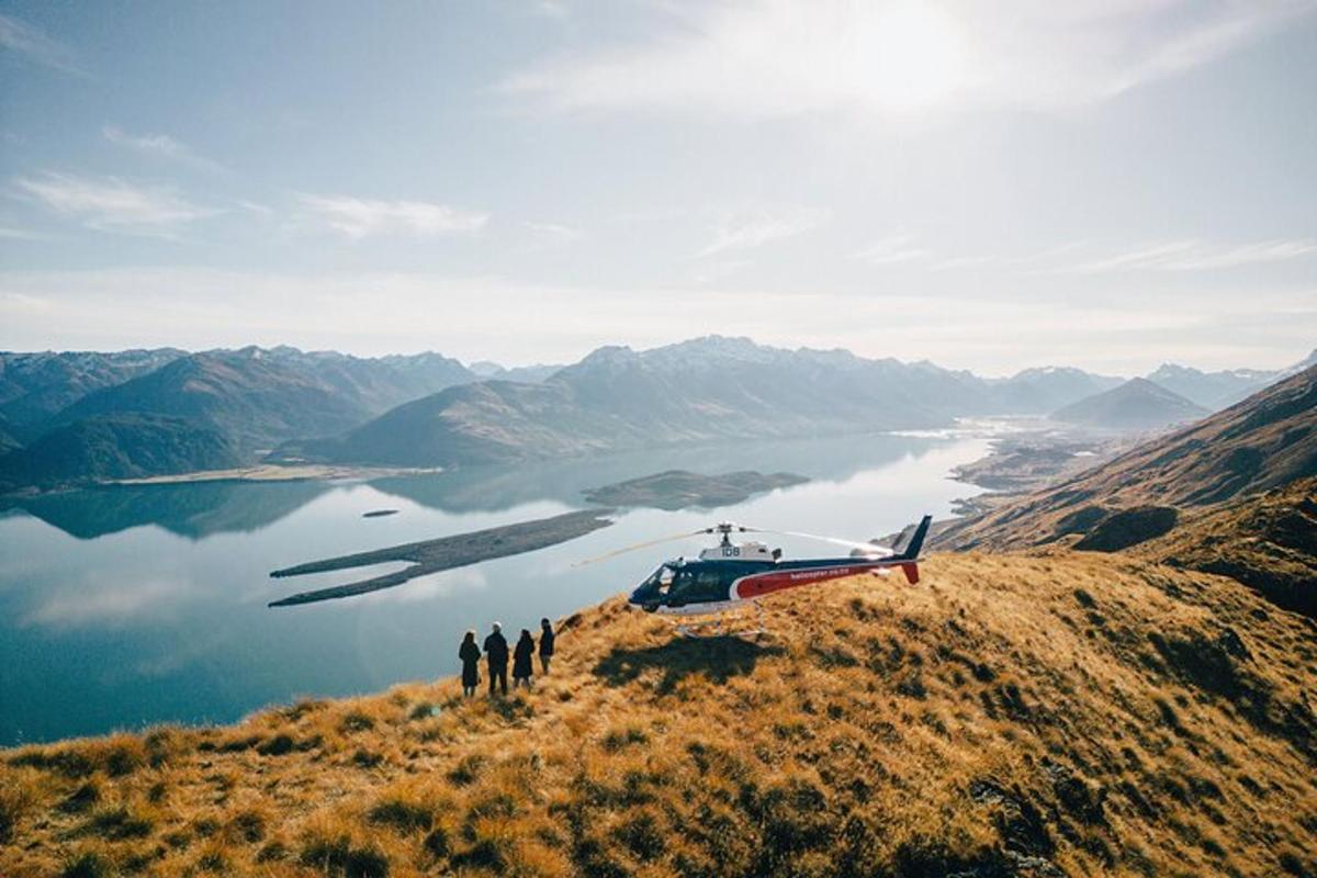 a group of people standing on a hill next to a helicopter