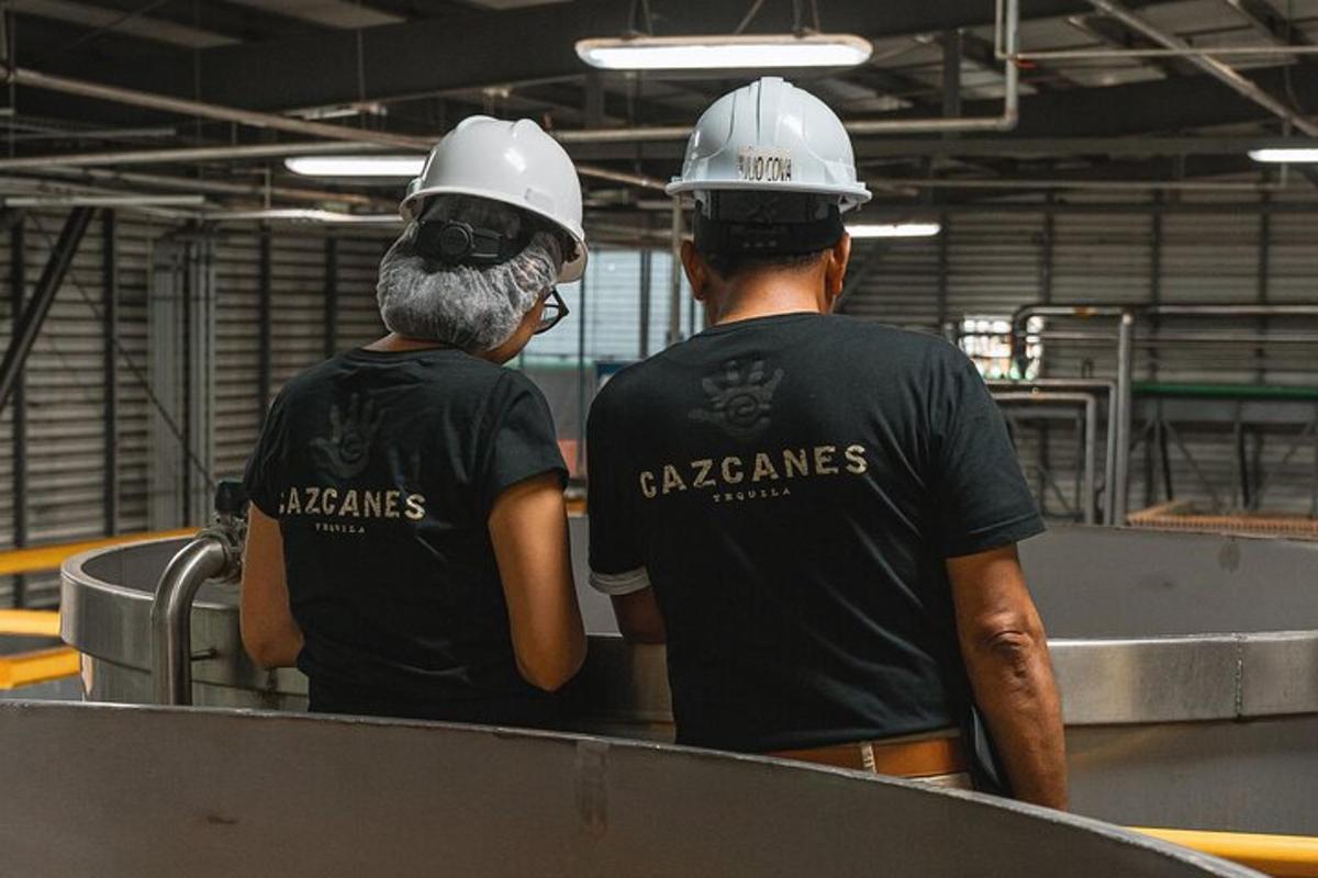 dois homens usando capacetes parados em uma fábrica