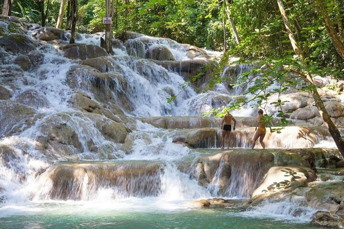 Una cascada con gente parada frente a ella.