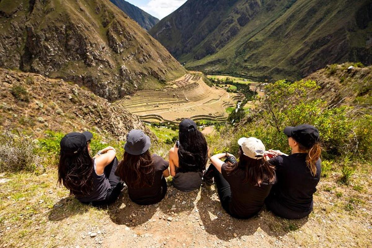 sekelompok gadis duduk di gunung sambil melihat ke arah lembah