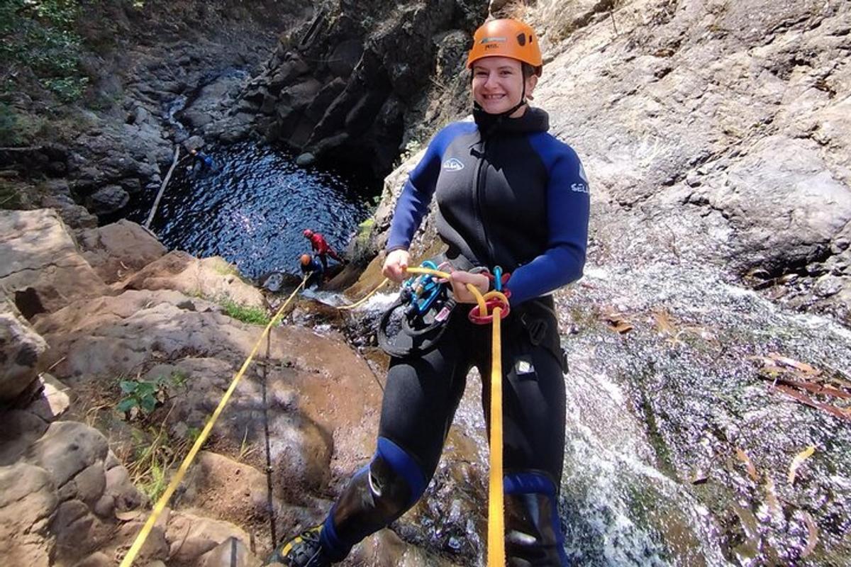 a man in a wetsuit is standing on a waterfall