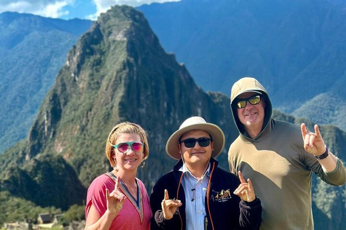 Un grupo de tres personas de pie frente a una montaña.