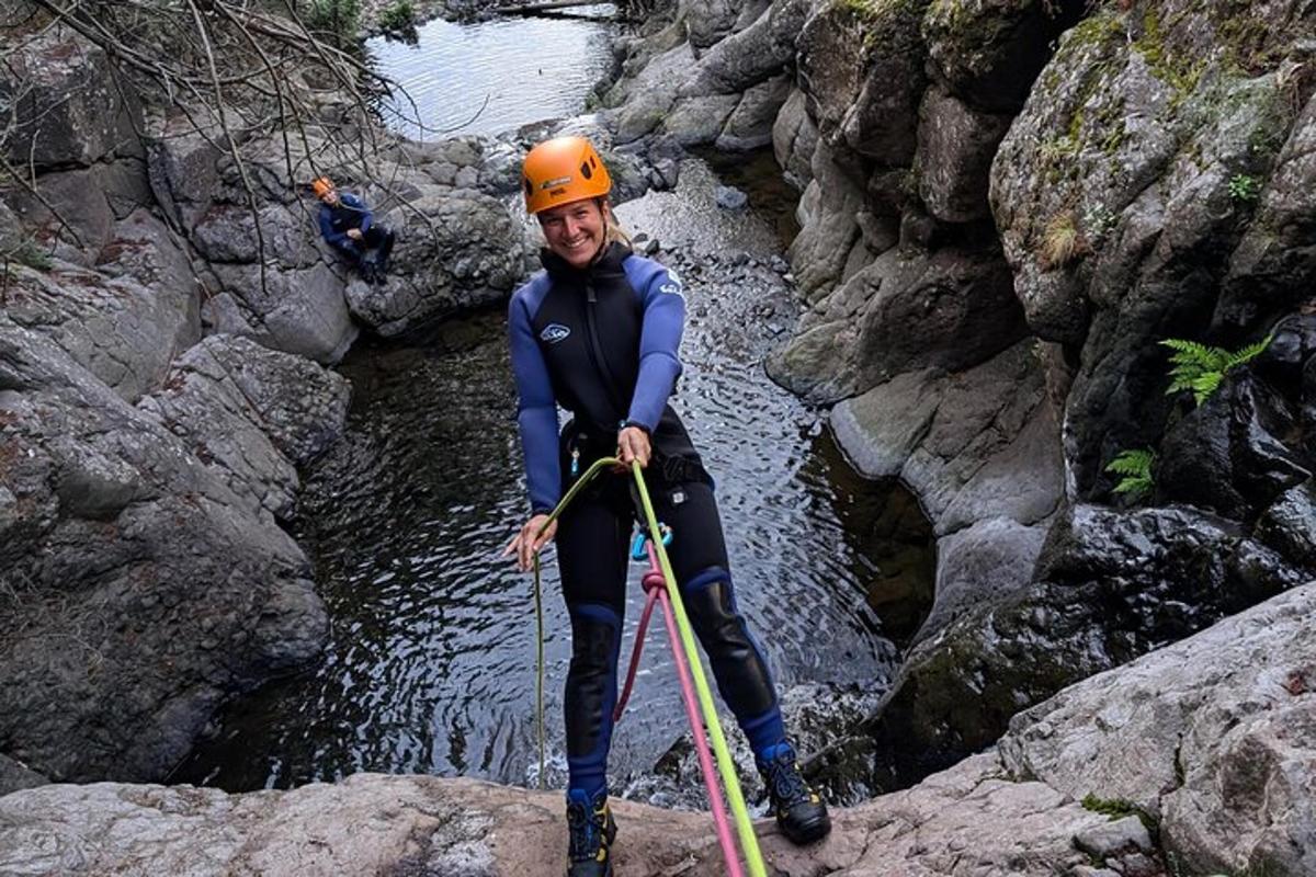 a man wearing an orange helmet standing on rocks in a river
