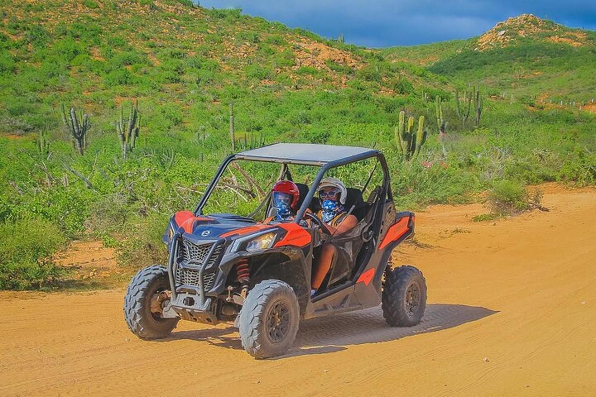 deux personnes conduisant un véhicule à quatre roues sur un chemin de terre