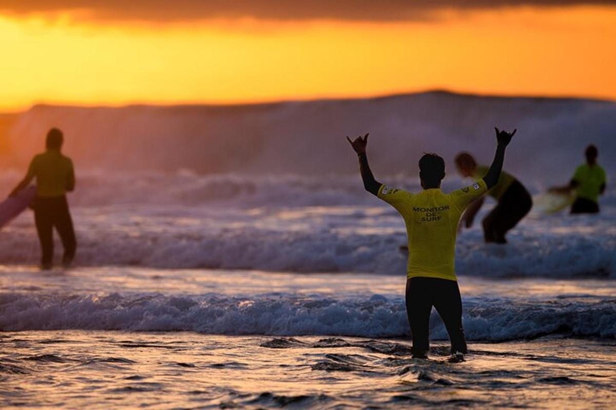Un grupo de personas de pie en la playa con los brazos en alto.