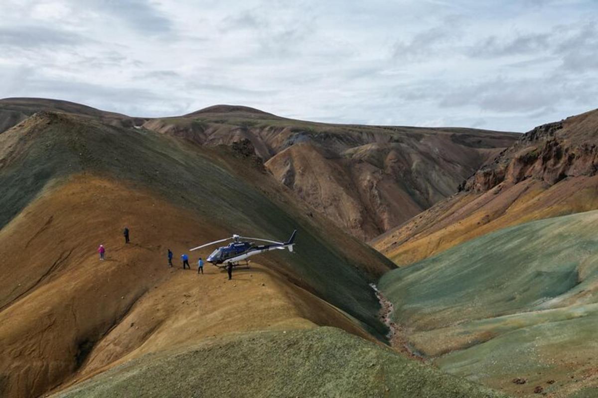 skupina ljudi, ki stojijo poleg helikopterja na gori
