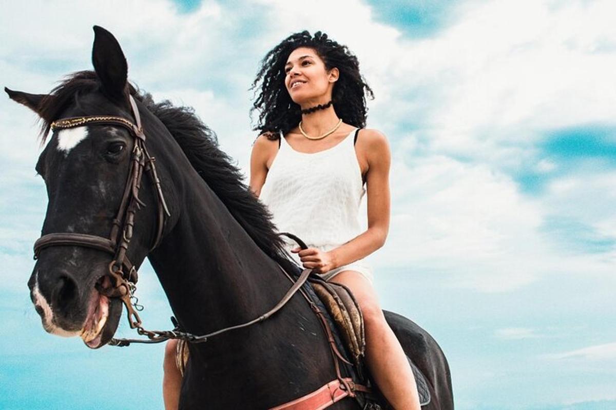 a woman riding a black horse on the beach