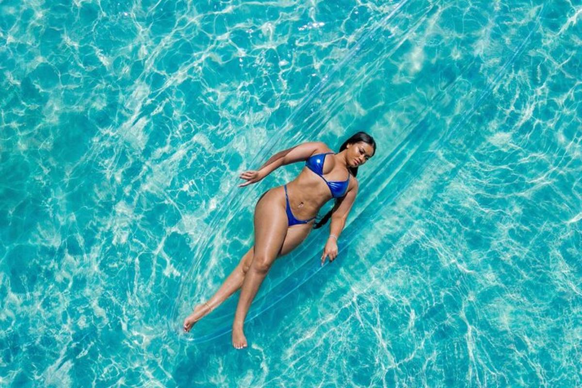 seorang wanita berbikini biru berbaring di papan selancar di air