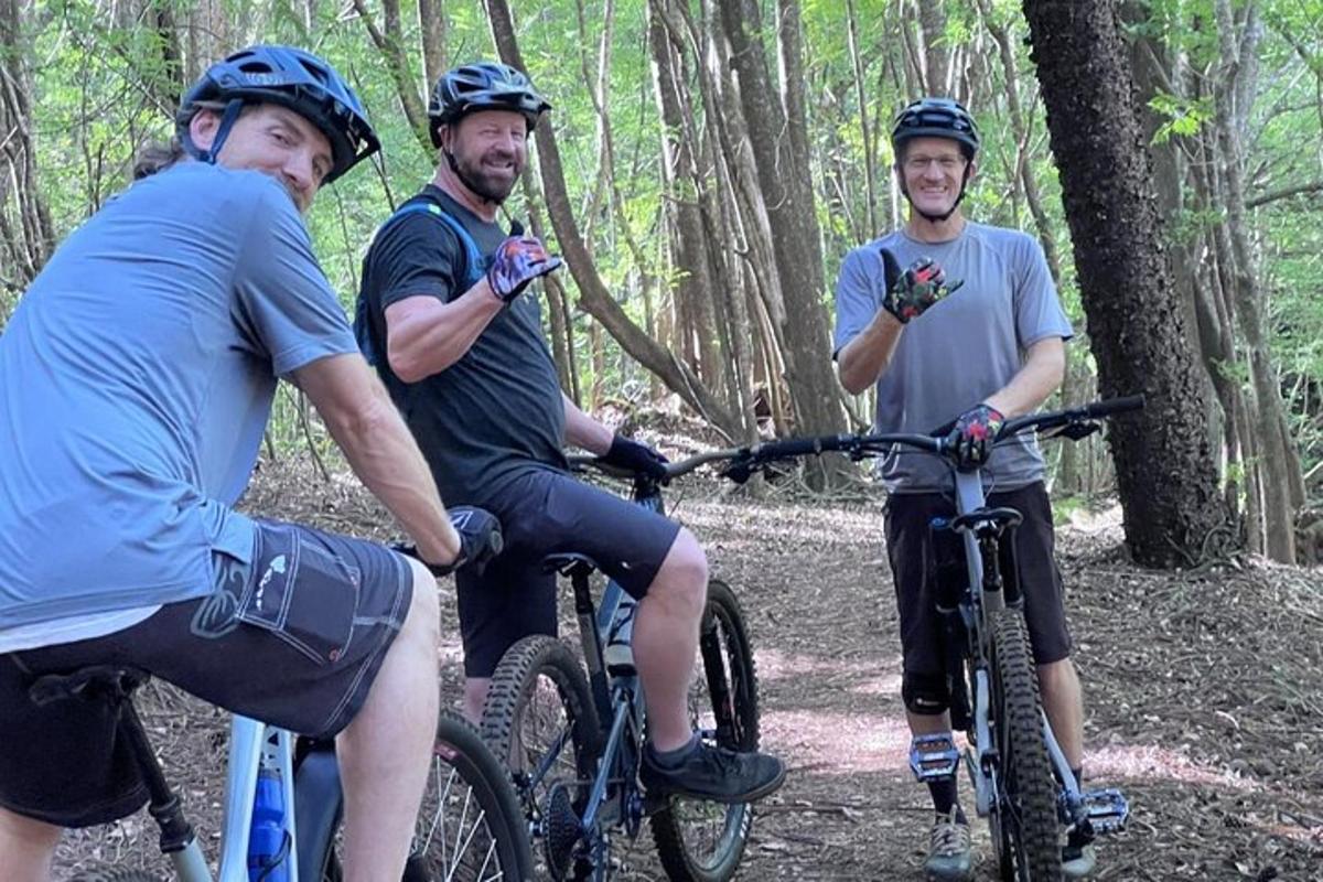 Tres hombres andando en bicicleta por un sendero en el bosque