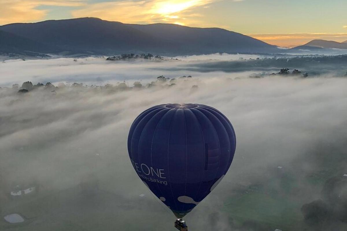 balon na vroč zrak, ki leti nad dolino, prekrito z meglo