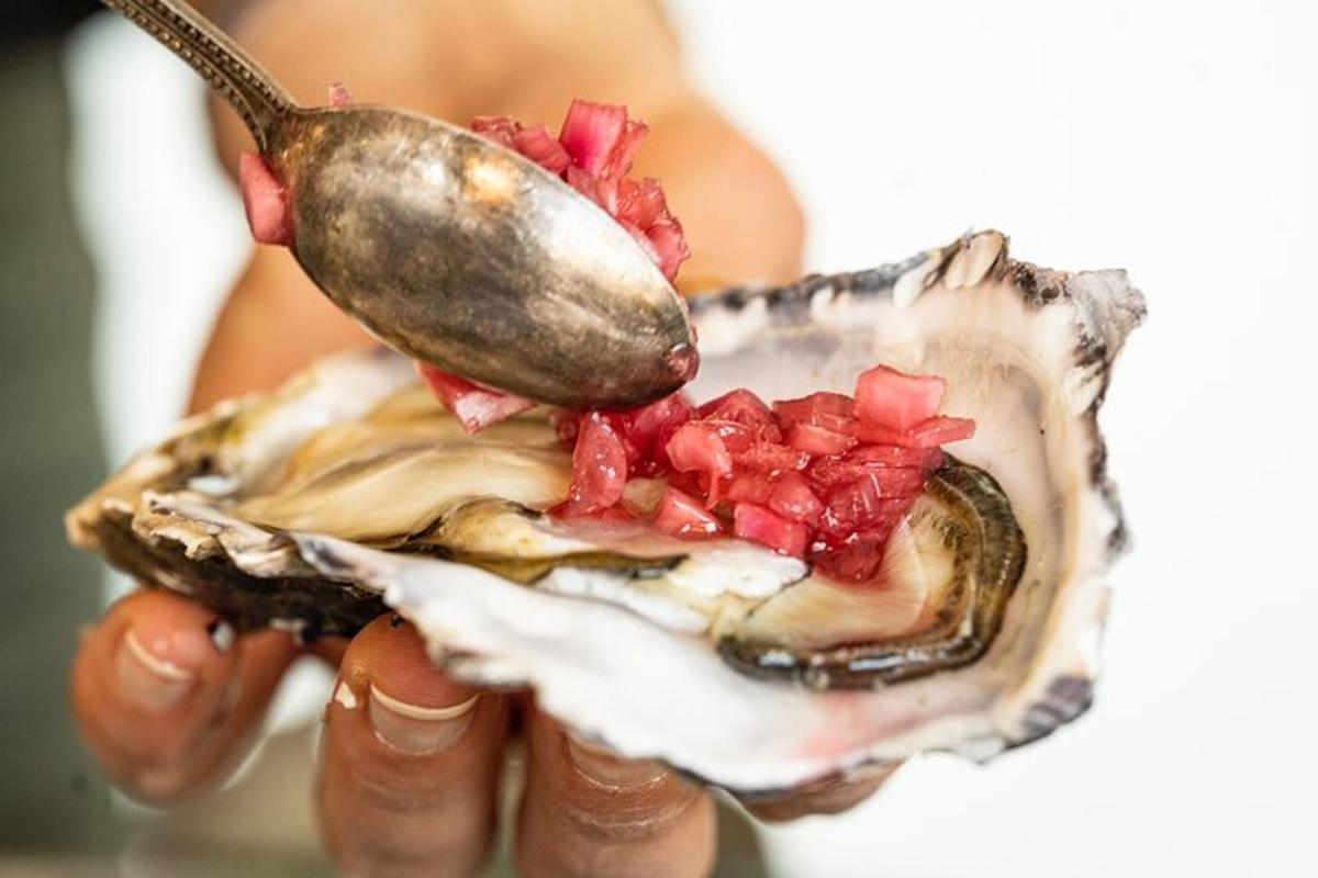 egy személy, aki kanállal és osztrigával tartja a kezében
