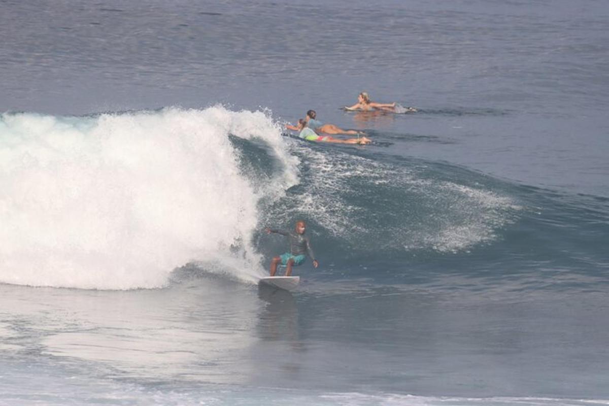 en gruppe mennesker, der rider på en bølge på surfbrætter i havet