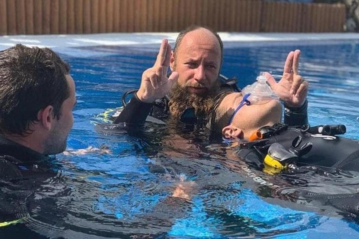 mężczyzna w basenie pokazujący znak pokoju