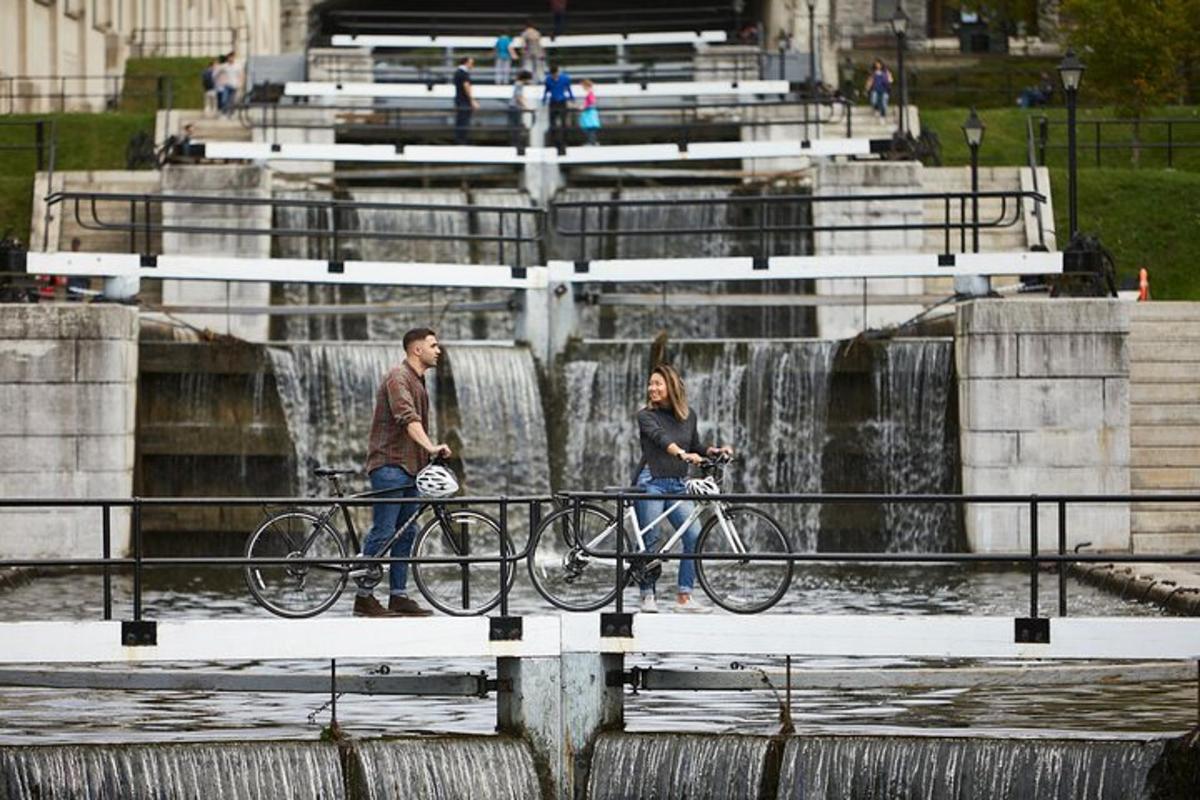 a man and woman walking their bikes in front of a waterfall