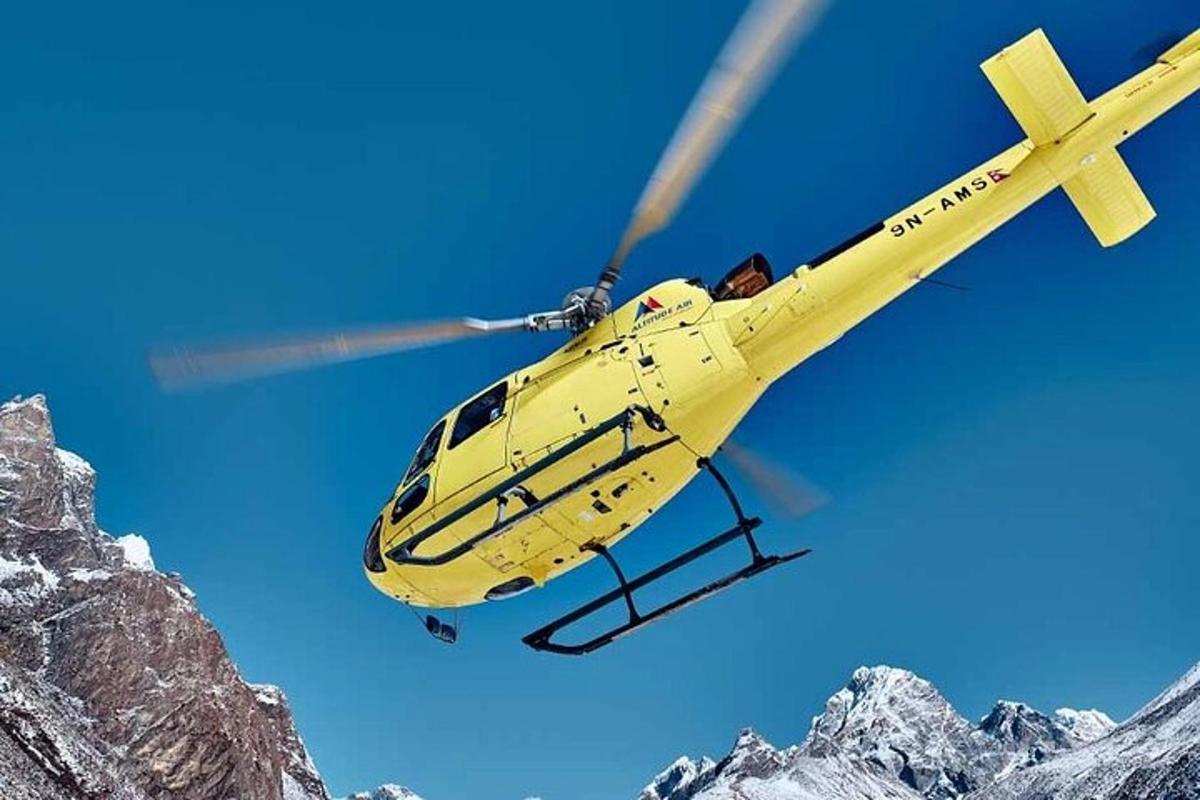 طائرة هليكوبتر صفراء تحلق فوق جبل مغطى بالثلوج