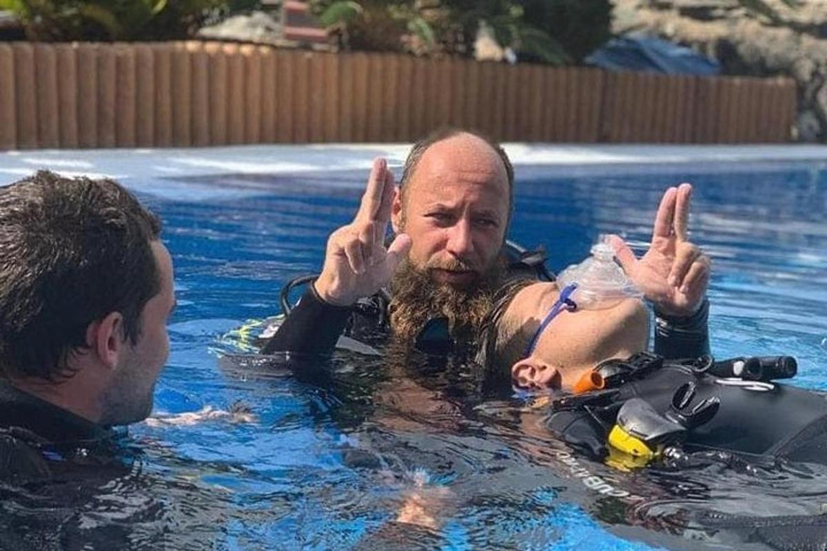 a man in a swimming pool giving the peace sign