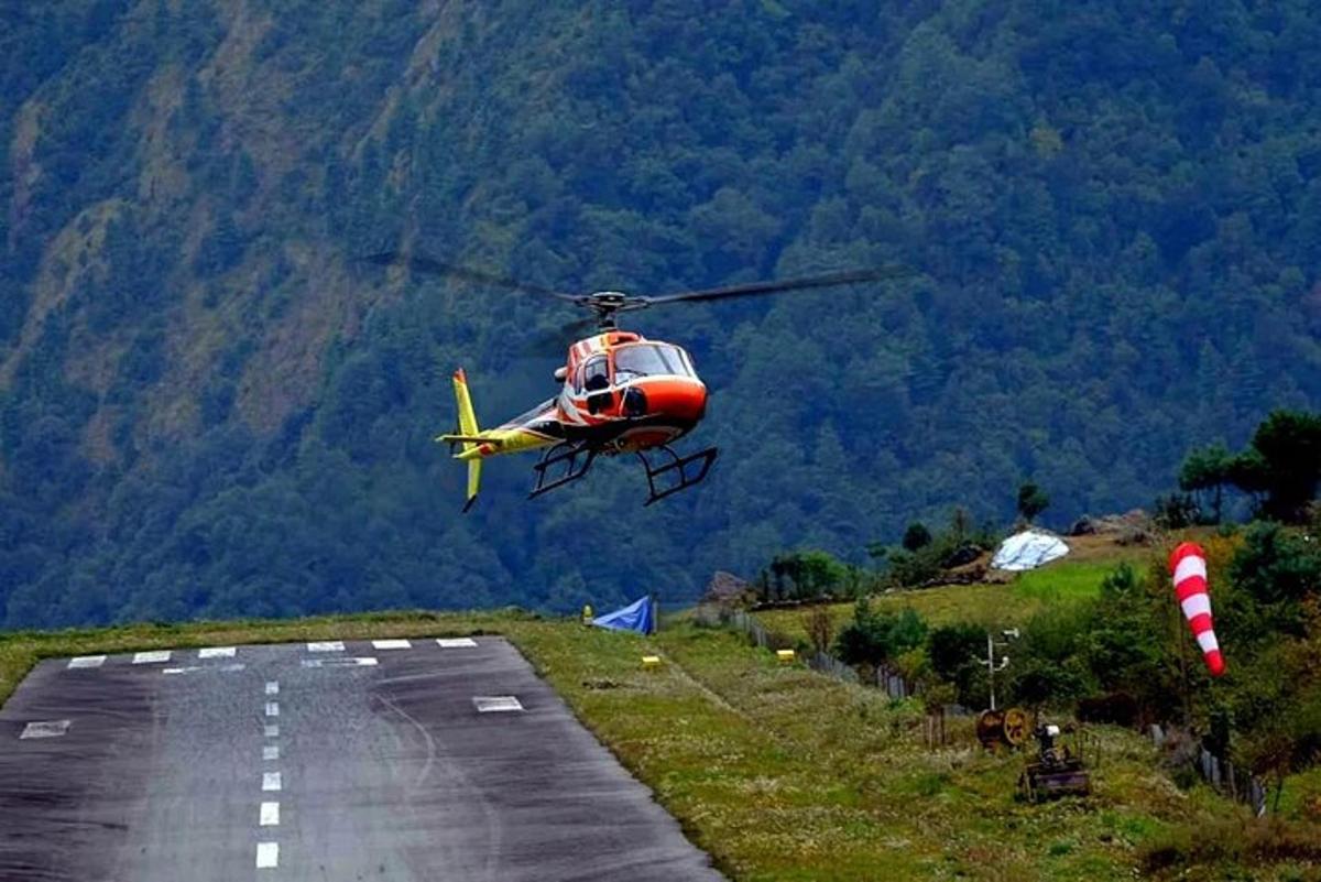 um helicóptero vermelho e amarelo voando sobre uma pista