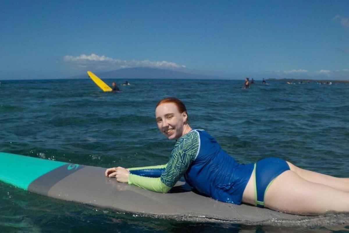 muž ležící na surfovém prkně v oceánu