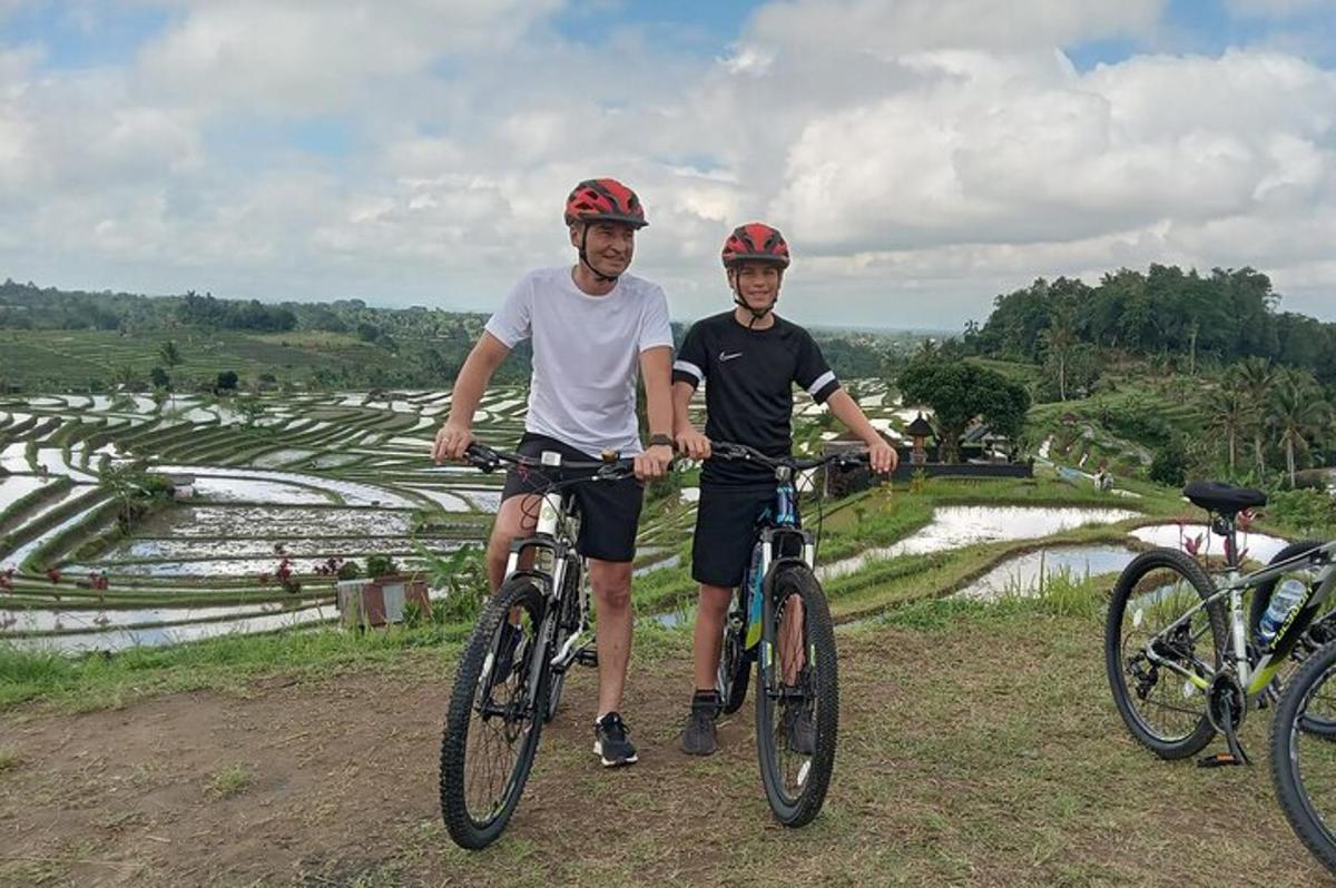 Dos hombres en bicicleta frente a un campo de arroz