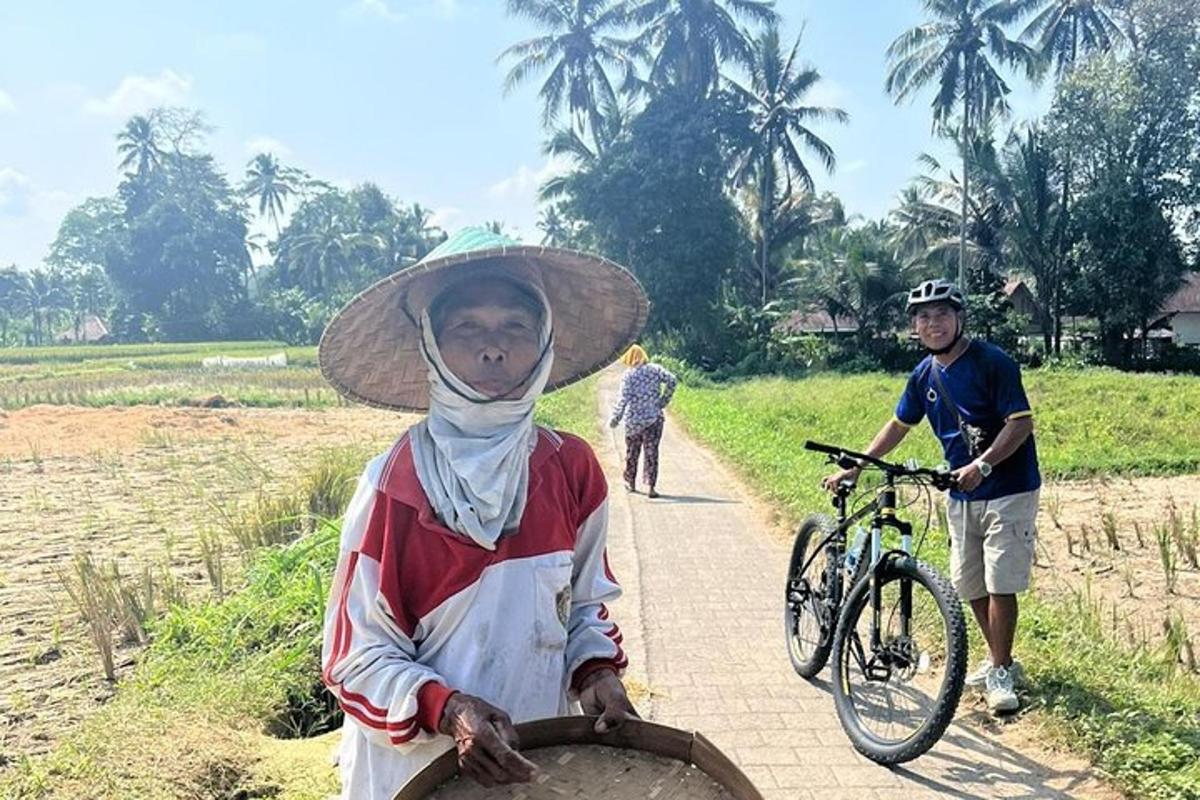 Una mujer con sombrero parada en un camino con una bicicleta.