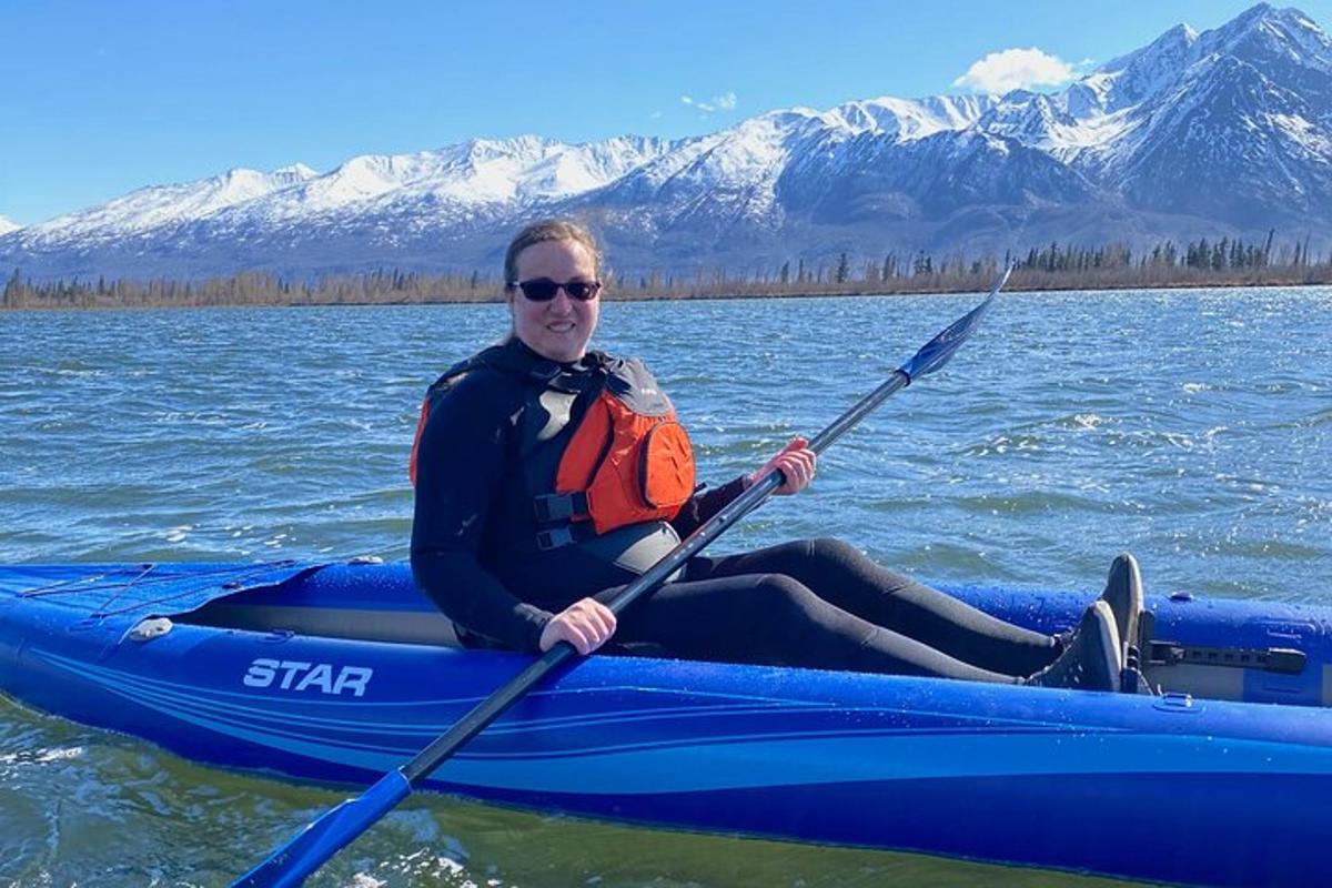 un uomo seduto su un kayak blu sull'acqua