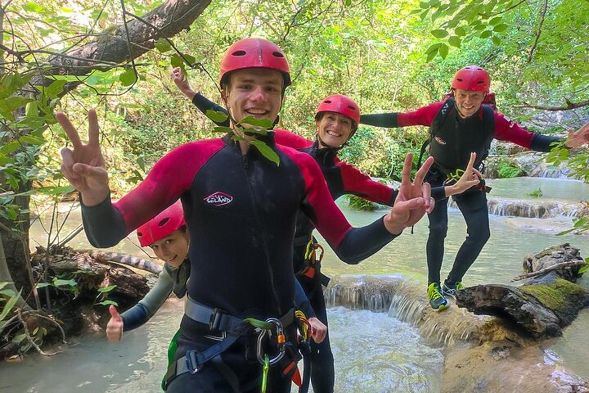 Eine Gruppe von Menschen macht auf einem Wasserfall das Peace-Zeichen.