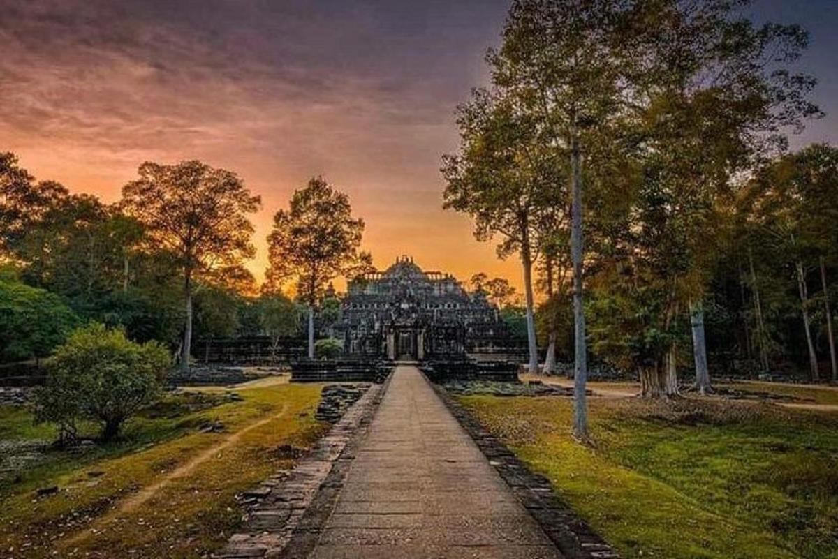 uma vista de um edifício em um parque ao pôr do sol