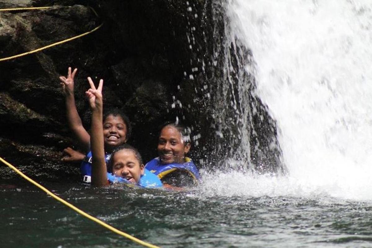 three children in the water in front of a waterfall