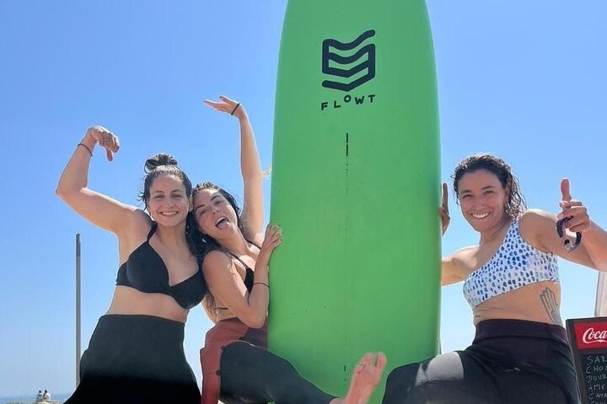 grupa žena sjedi na plaži s daskom za surfanje