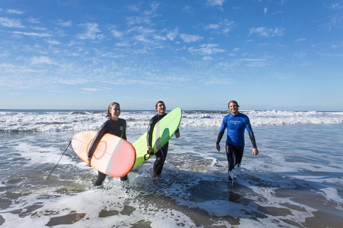 three people walking into the ocean with their surfboards