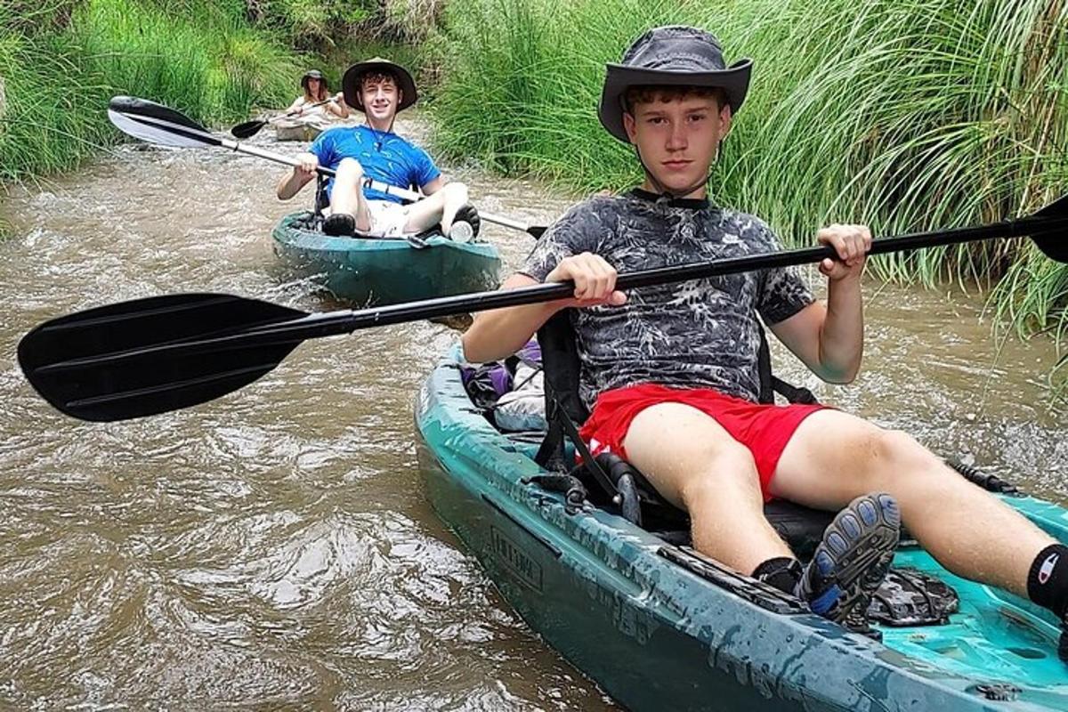 zwei junge Männer fahren mit dem Kajak einen Fluss hinunter