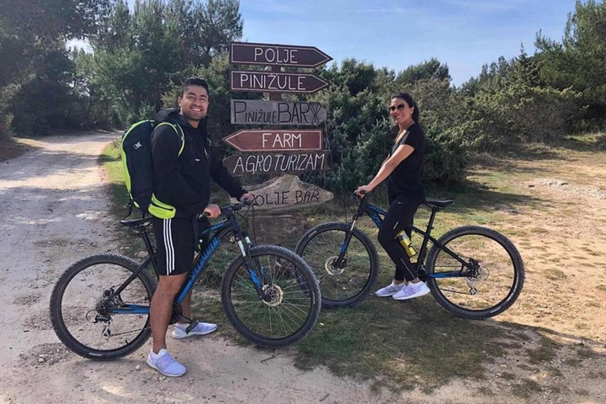 two people standing next to their bikes in front of a sign