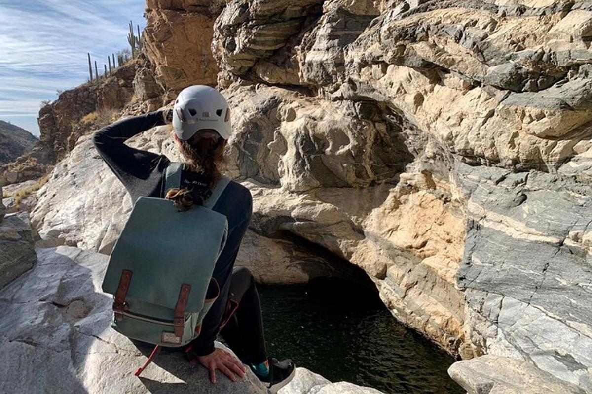 a woman is sitting on a rock with a helmet