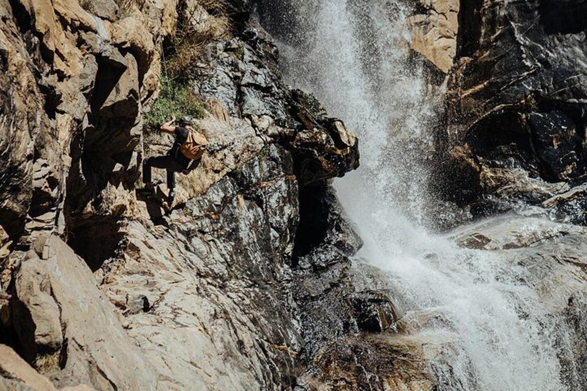 a person standing next to a waterfall on a mountain