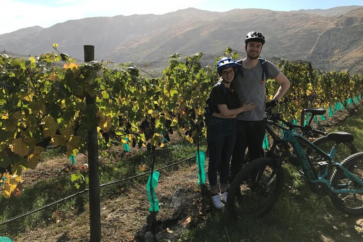 un uomo e una donna in piedi accanto a una bicicletta in un vigneto