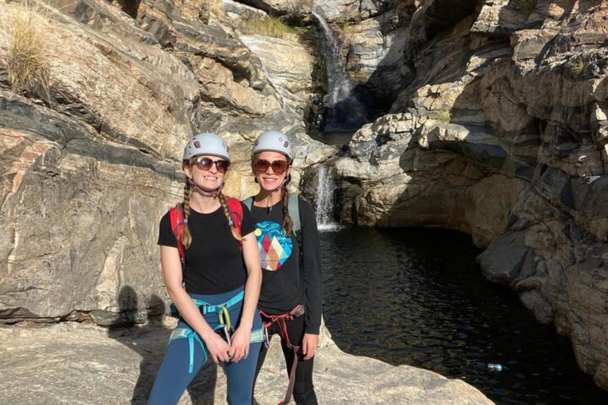 two people posing for a picture in front of a waterfall