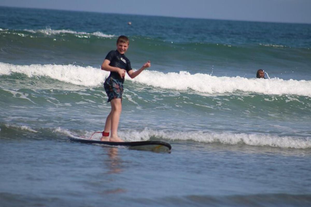 um menino em pé em uma prancha de surfe no oceano
