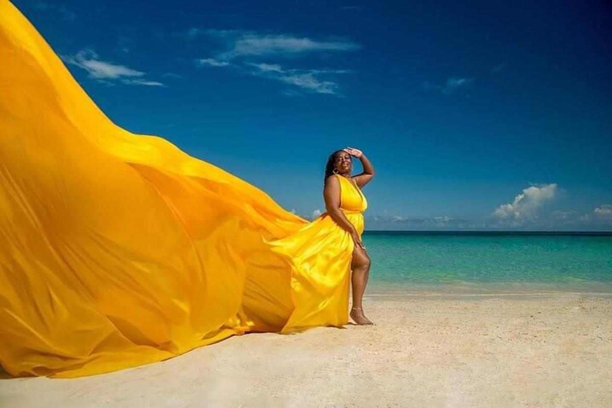 a woman in a yellow dress standing on a beach