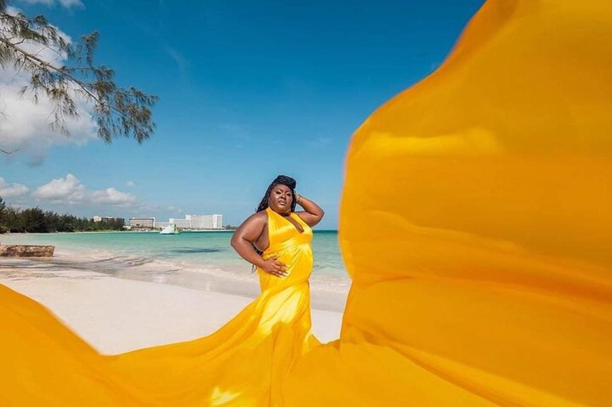 a woman in a yellow dress standing on a beach