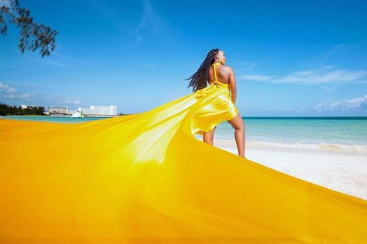 a woman in a yellow dress standing on a beach