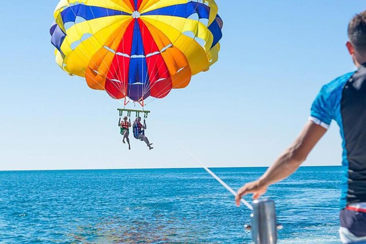 un uomo che vola con un paracadute colorato sopra l'oceano
